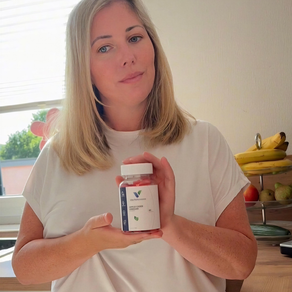 Frau hält eine Dose Vita Performance Apfelessig-Gummies in der Küche